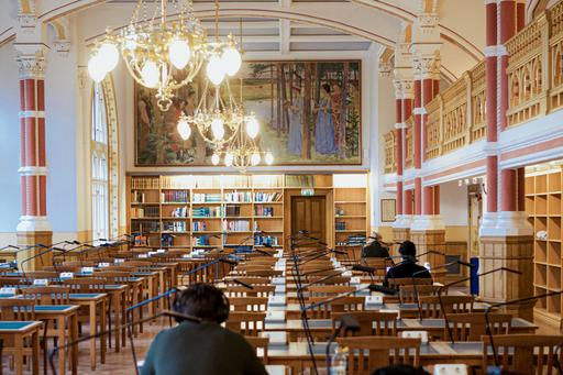 Reading room with bookshelves, chandeliers and study spaces.
